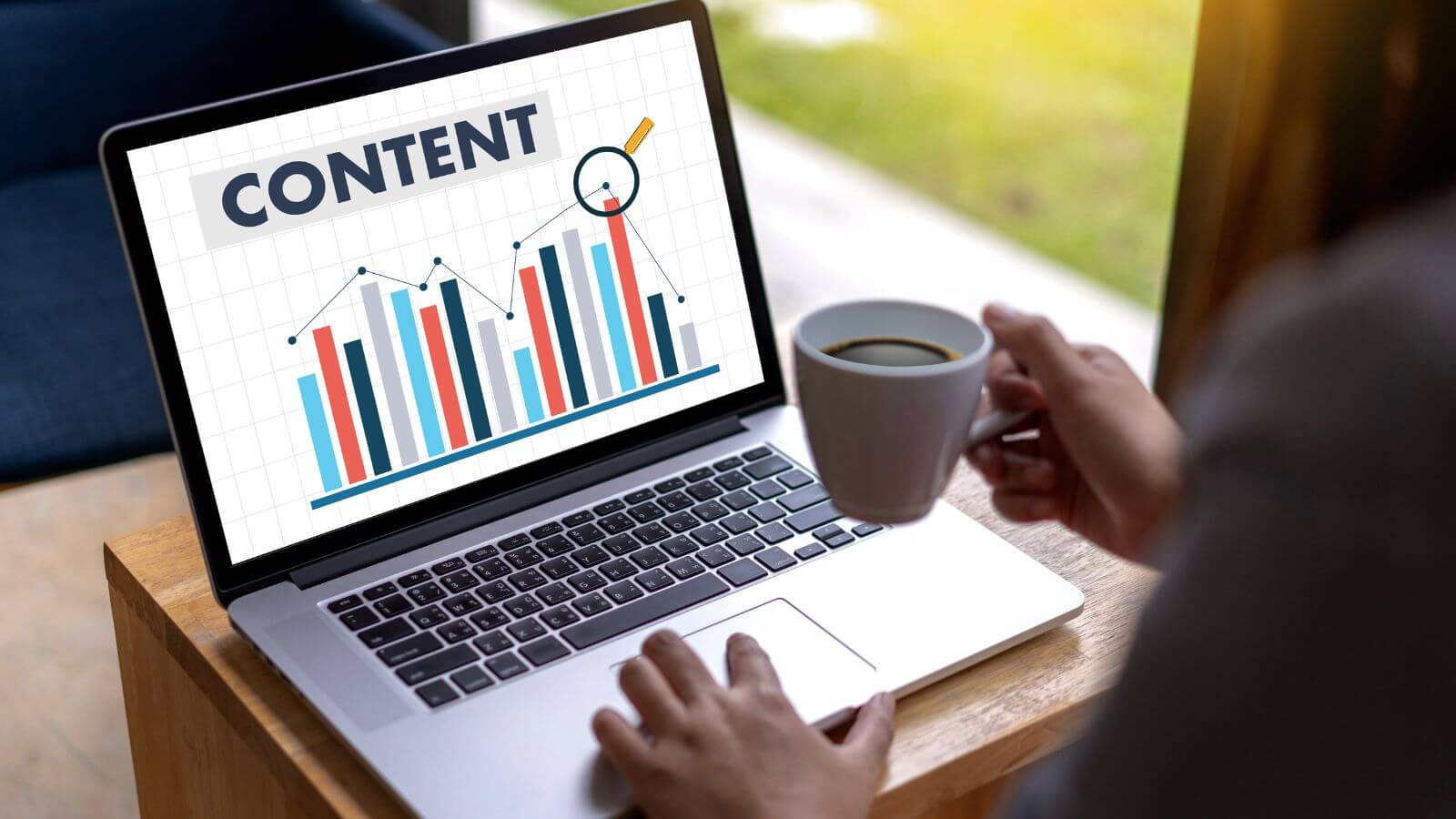 Laptop showing content performance analytics with user holding coffee cup Laptop showing content performance analytics with user holding coffee cup