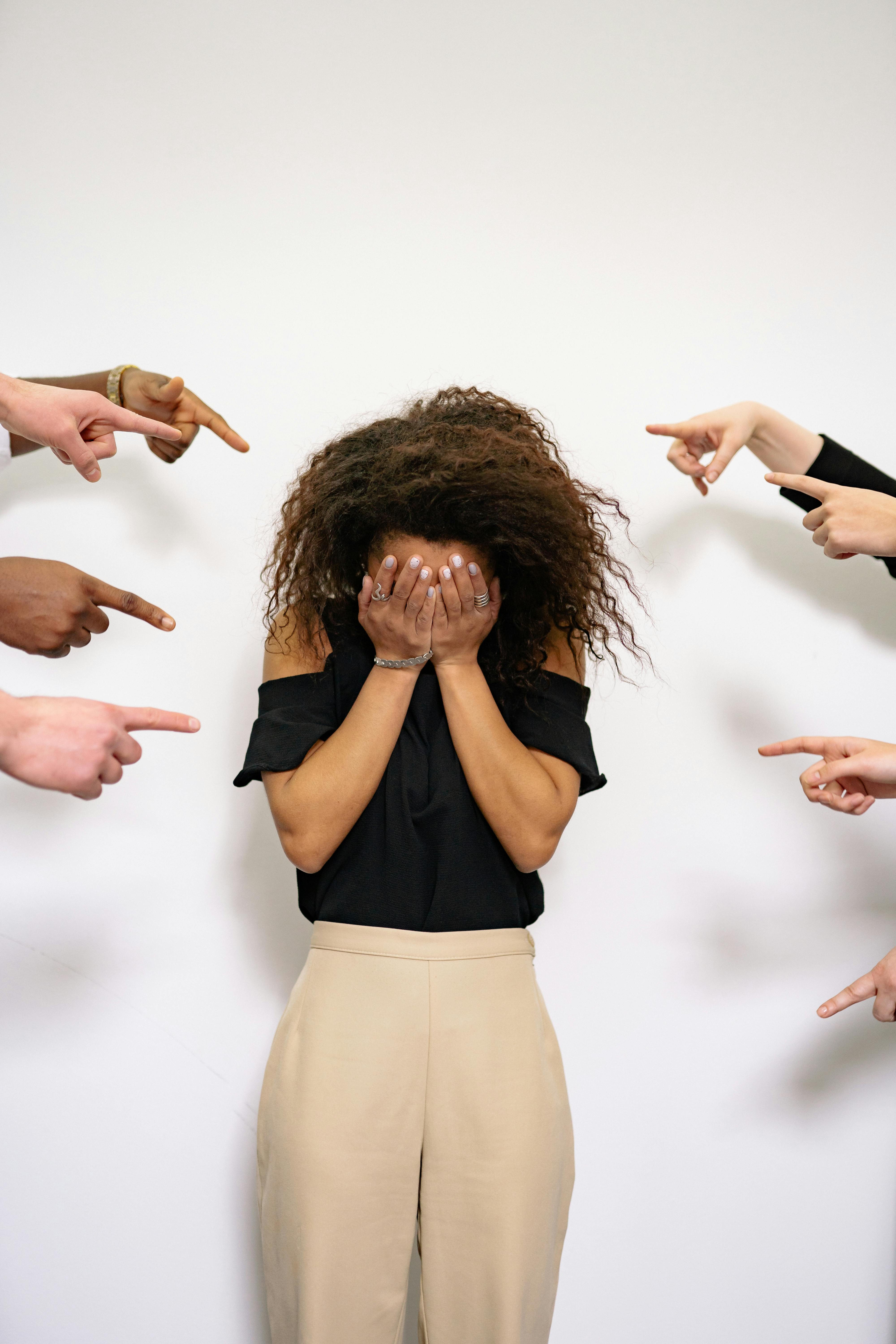 businesswoman hiding being pointed at businesswoman hiding being pointed at
