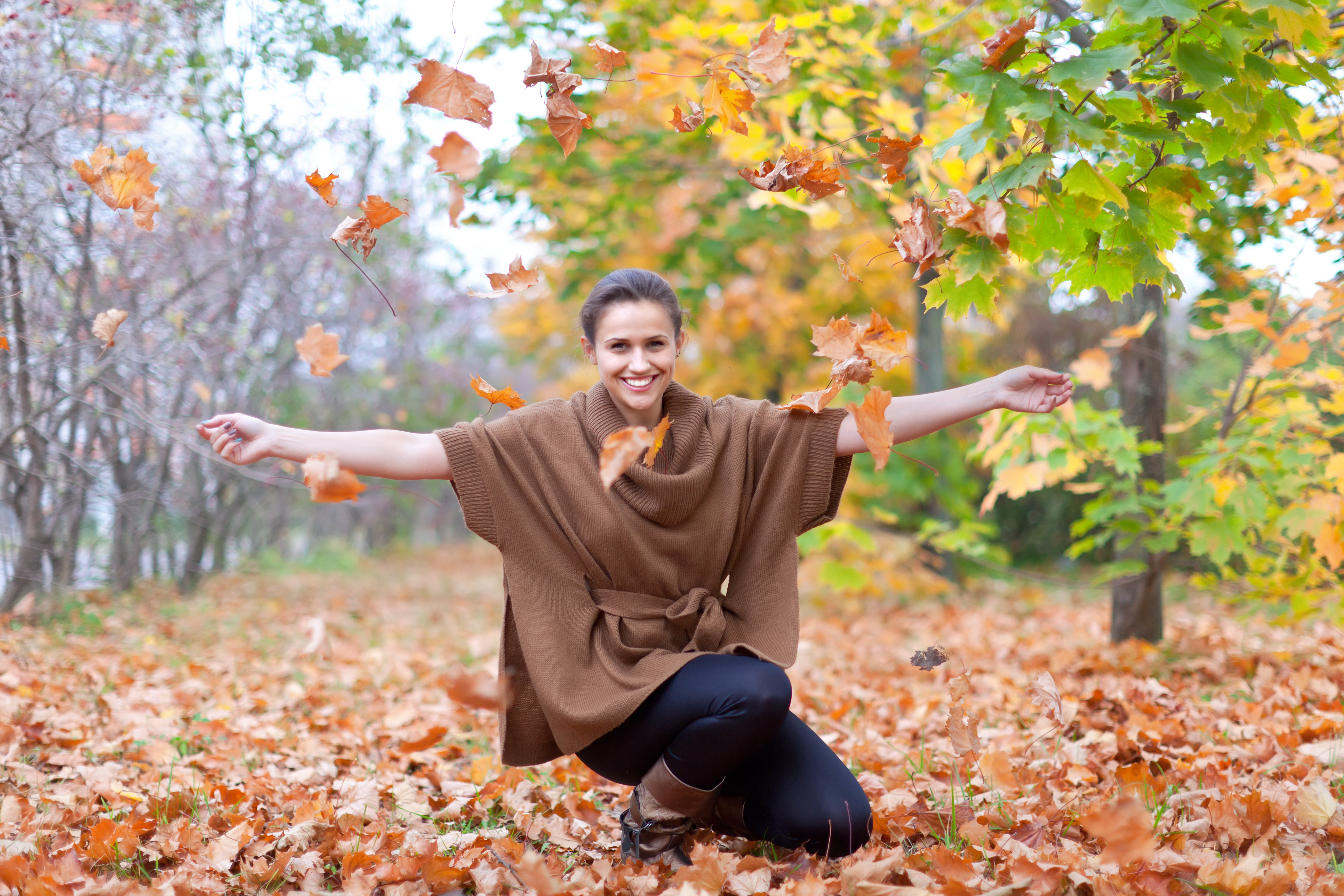 woman throwing autumn leaves
