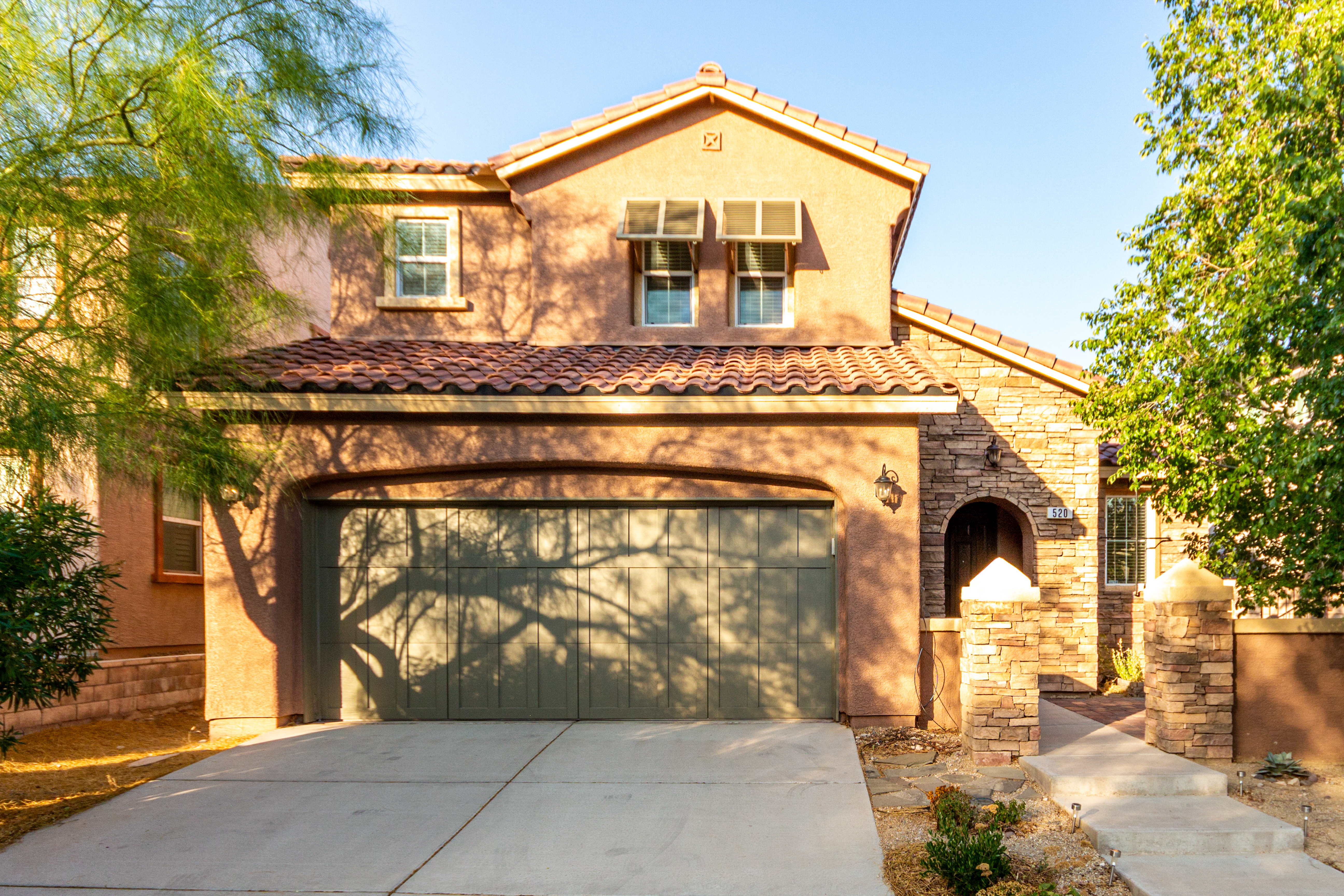 Front exterior of two‑story Spanish‑style home at 520 Ivy Spring St, Summerlin—stone accents, tile roof, sage‑green garage door, and desert landscaping in morning light Front exterior of two‑story Spanish‑style home at 520 Ivy Spring St, Summerlin—stone accents, tile roof, sage‑green garage door, and desert landscaping in morning light