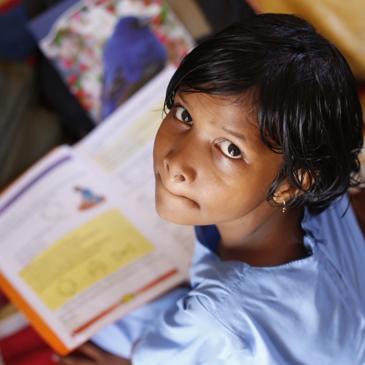 Child studying with a textbook, looking up with a concerned expression, highlighting the impact of financial stress on academic focus and emotional well-being.