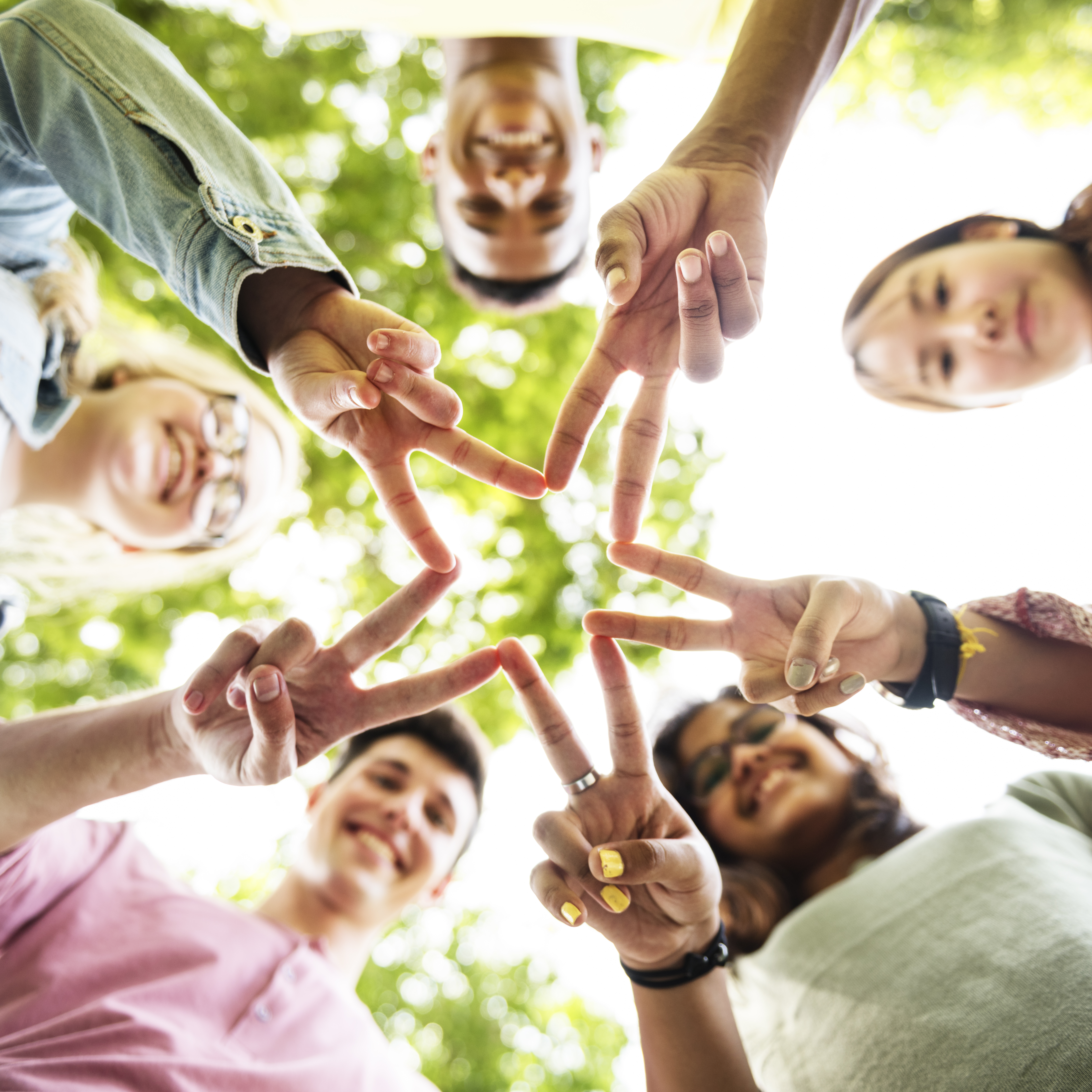 several teens looking down into the camera forming a star with their fingers