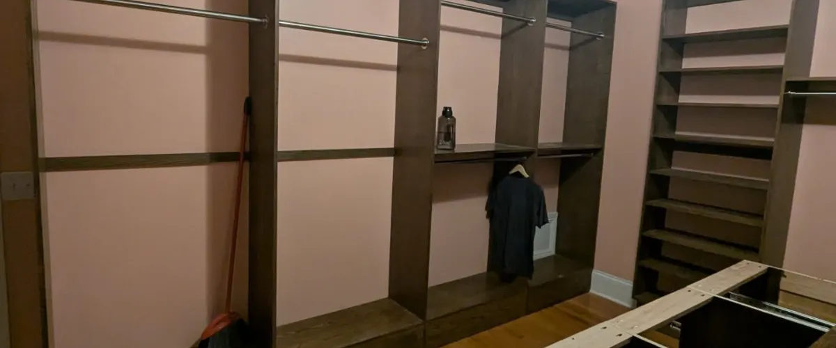 A modern walk-in closet with built-in hanging storage and shelves for a clean and spacious look. A modern walk-in closet with built-in hanging storage and shelves for a clean and spacious look.