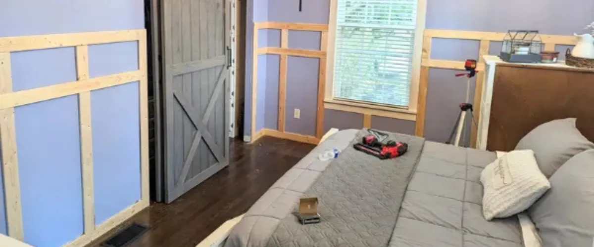 Bedroom under renovation with wall trim being installed and barn-style sliding door Bedroom under renovation with wall trim being installed and barn-style sliding door