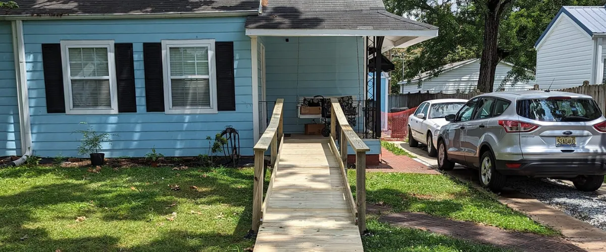 Newly installed wooden accessibility ramp leading to the front porch of a blue house Newly installed wooden accessibility ramp leading to the front porch of a blue house