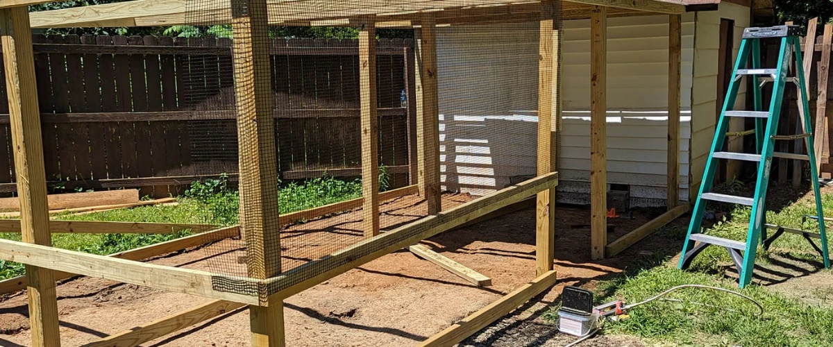 Framed outdoor wooden enclosure under construction with tools and ladder nearby Framed outdoor wooden enclosure under construction with tools and ladder nearby