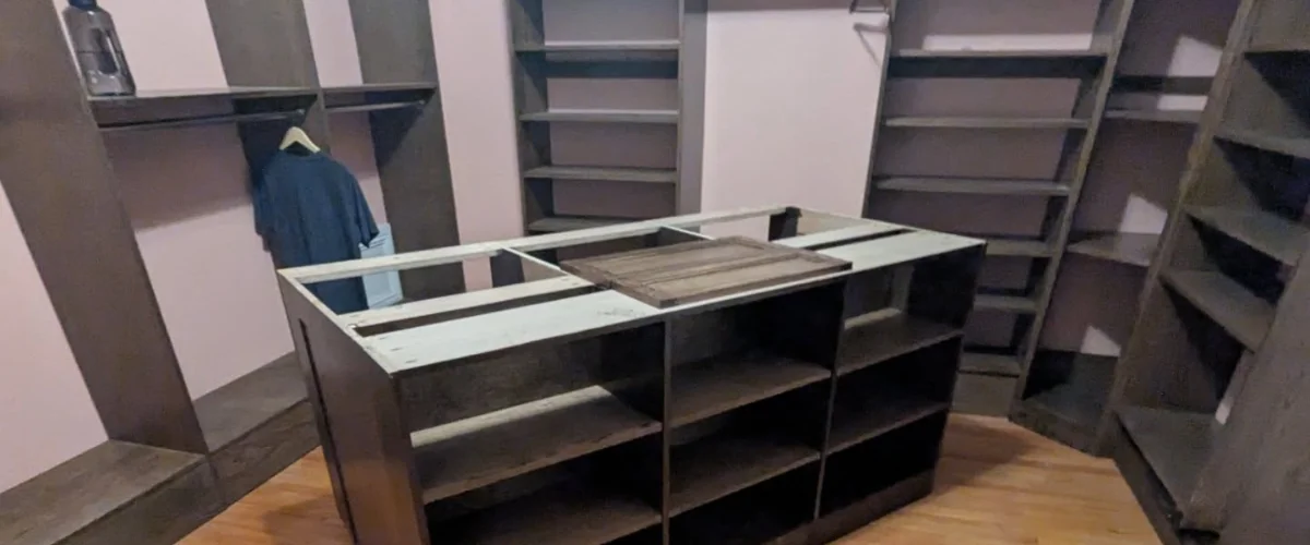 Custom walk-in closet featuring a center island with storage and surrounding shelving