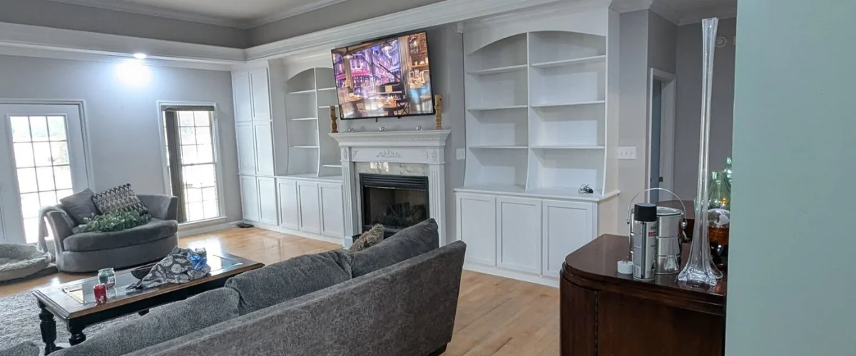 Custom built-in living room shelving with fireplace and wall-mounted TV.”