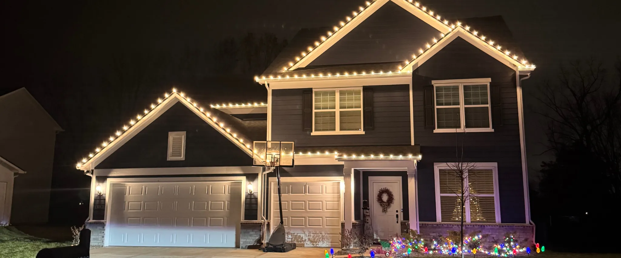 Modern two-story home decorated with warm white permanent Christmas lights at night Modern two-story home decorated with warm white permanent Christmas lights at night