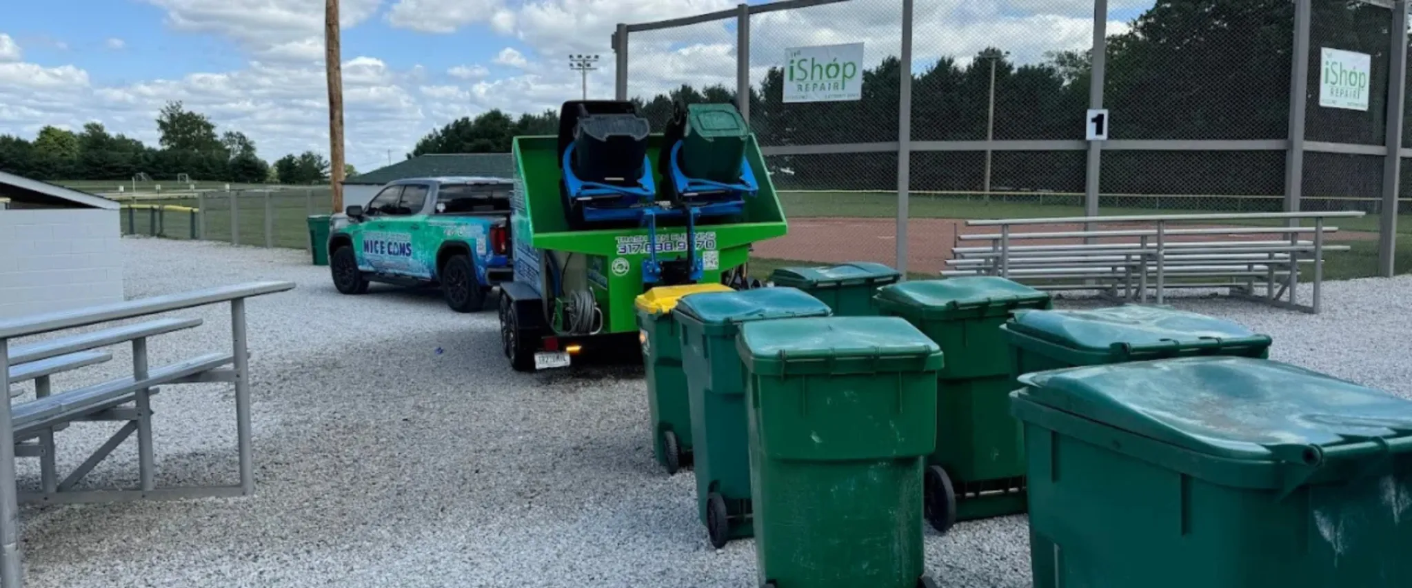 Trash bin cleaning trailer parked near a sports field with multiple trash bins lined up Trash bin cleaning trailer parked near a sports field with multiple trash bins lined up