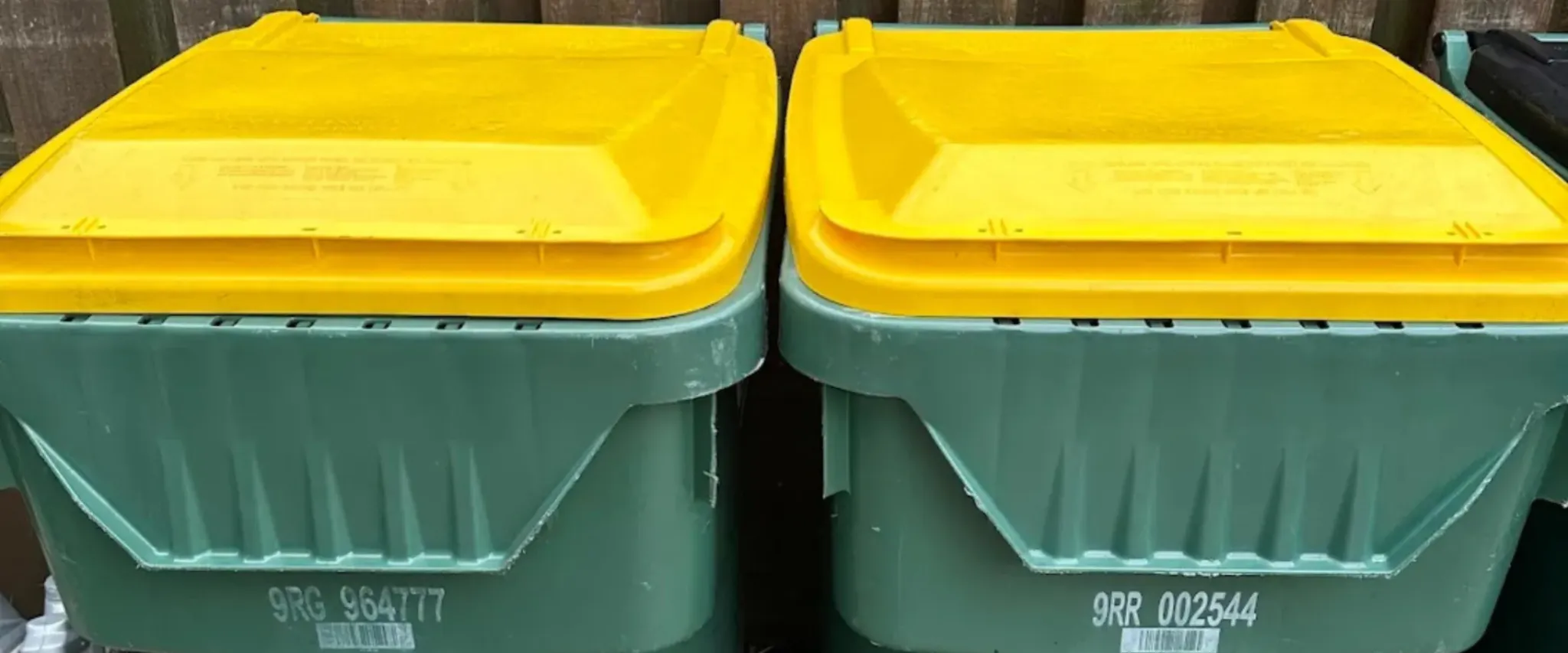 Close-up image of green trash bins with bright yellow lids, ready for service Close-up image of green trash bins with bright yellow lids, ready for service