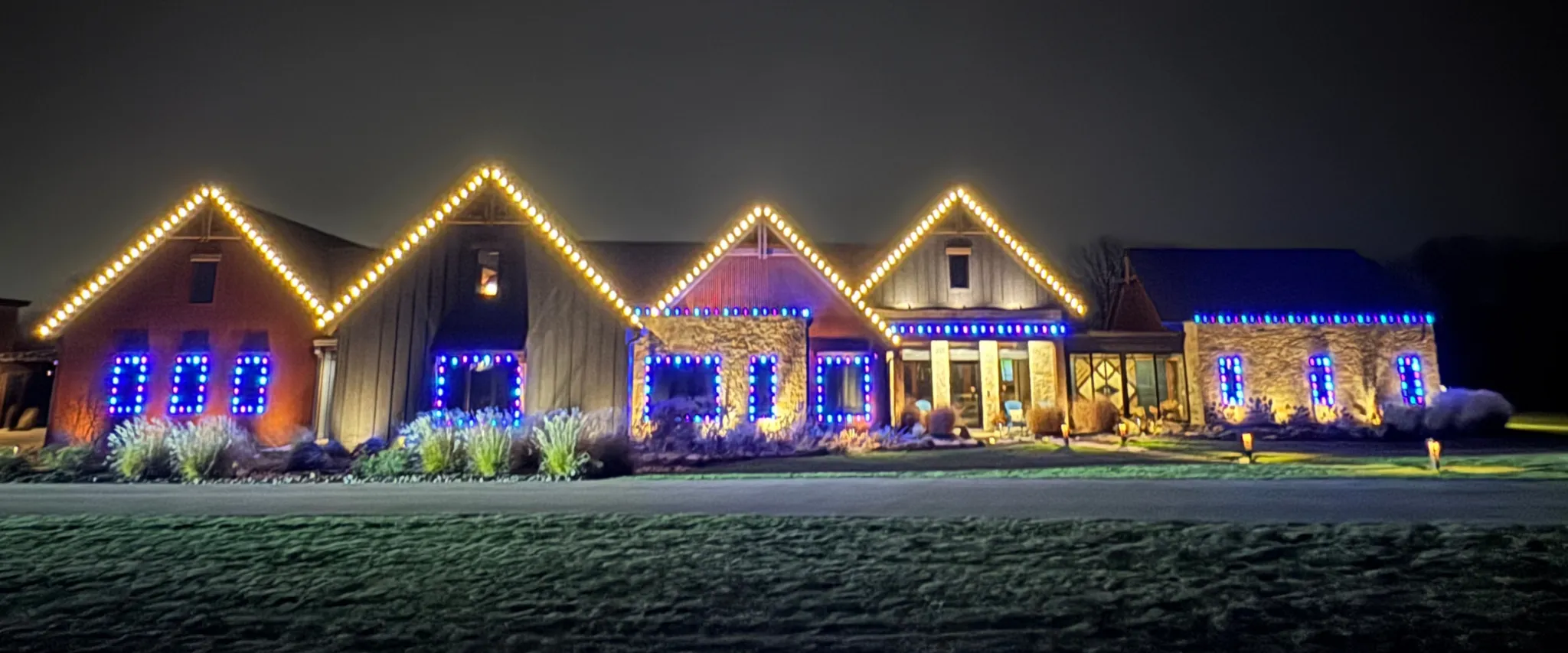 Expansive home with yellow and blue permanent holiday lights illuminating the exterior Expansive home with yellow and blue permanent holiday lights illuminating the exterior