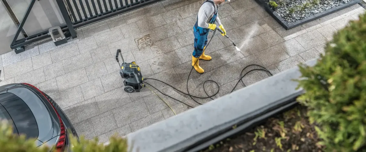 Professional cleaning a driveway using a pressure washer, removing built-up dirt and grime Professional cleaning a driveway using a pressure washer, removing built-up dirt and grime