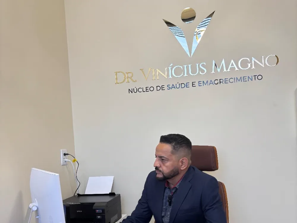 Dr. Vinícius no consultório da unidade Fleming, com a parede do Núcleo de Saúde e Emagrecimento