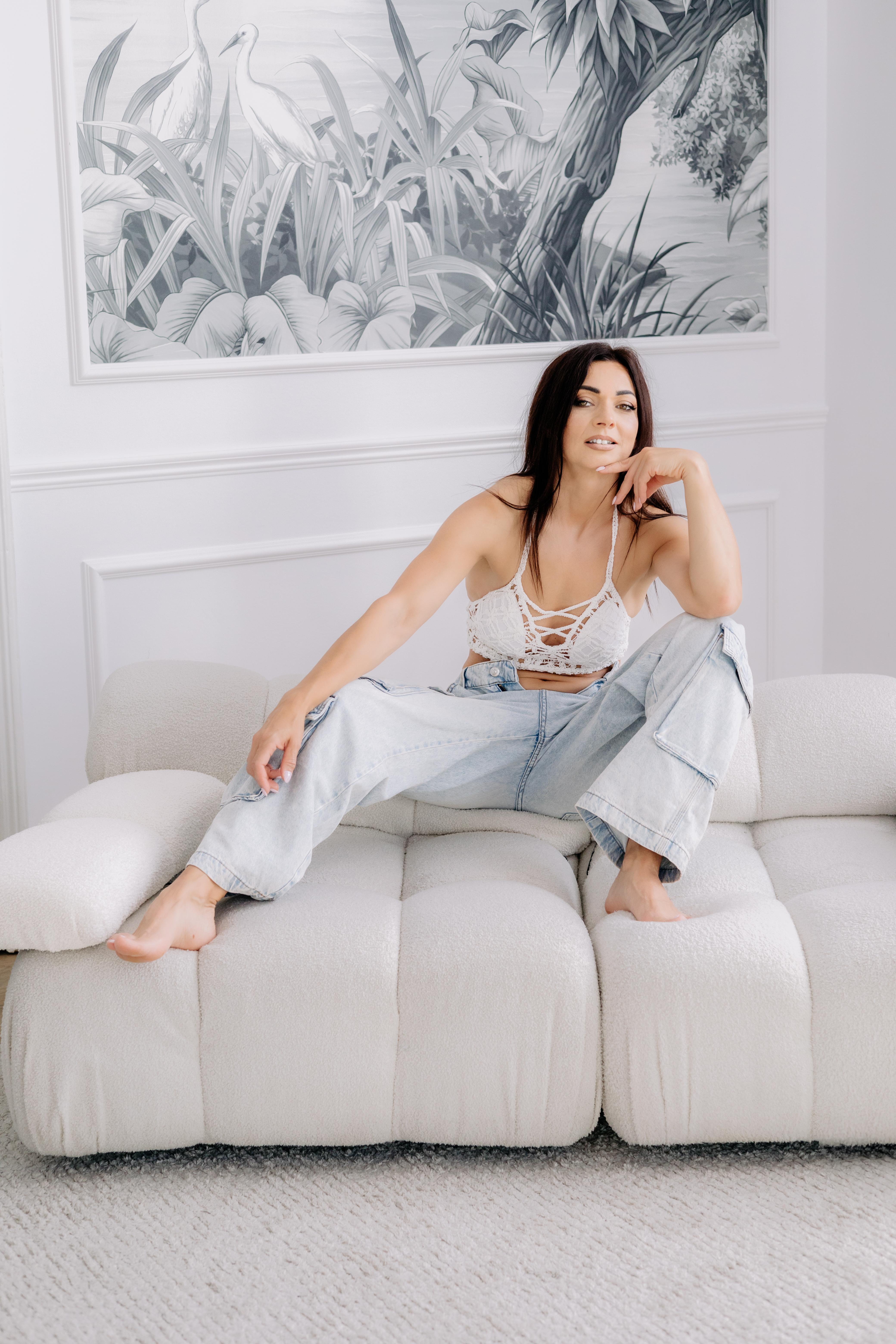 woman on the couch wearing white top and denim jeans