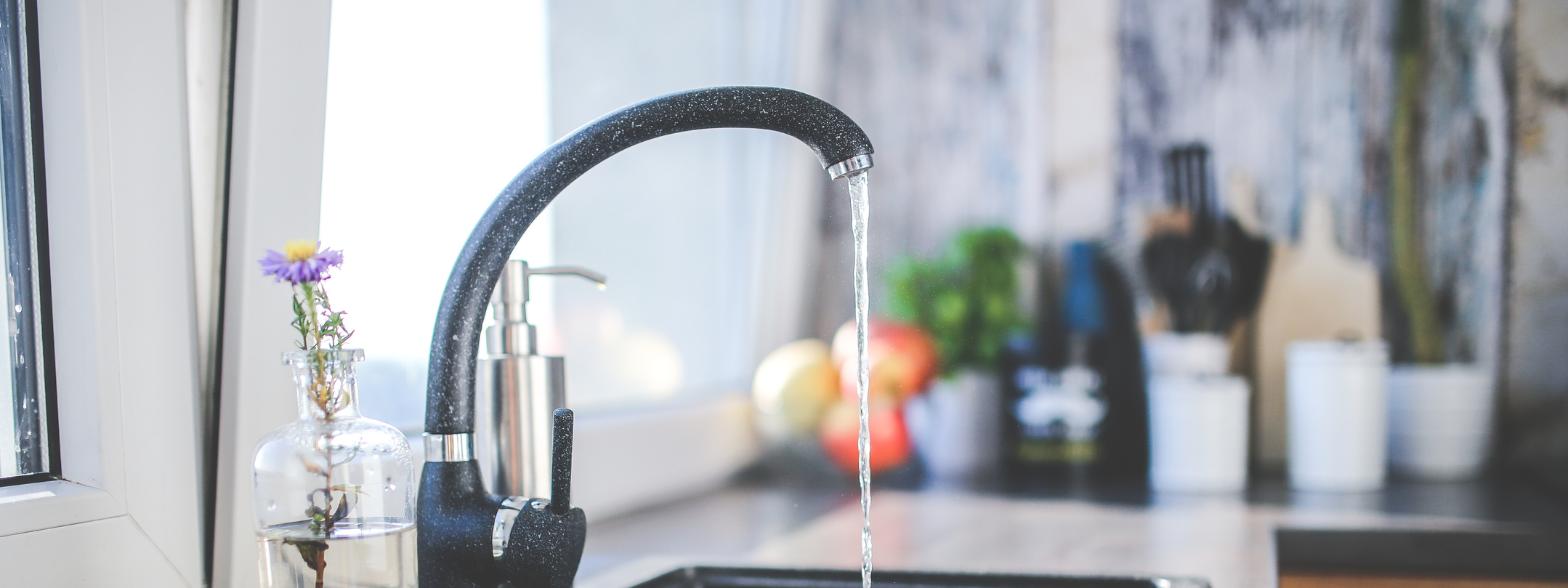 Modern kitchen sink with a black faucet running water, symbolizing water pressure issues that may indicate hidden plumbing leaks or pipe blockages. Modern kitchen sink with a black faucet running water, symbolizing water pressure issues that may indicate hidden plumbing leaks or pipe blockages.