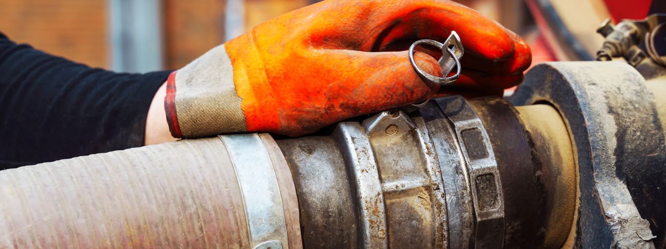 Close-up of a plumber’s gloved hand working on a large industrial sewer pipe connection. Proper maintenance and professional sewer line services help prevent backups and ensure efficient wastewater flow. Close-up of a plumber’s gloved hand working on a large industrial sewer pipe connection. Proper maintenance and professional sewer line services help prevent backups and ensure efficient wastewater flow.