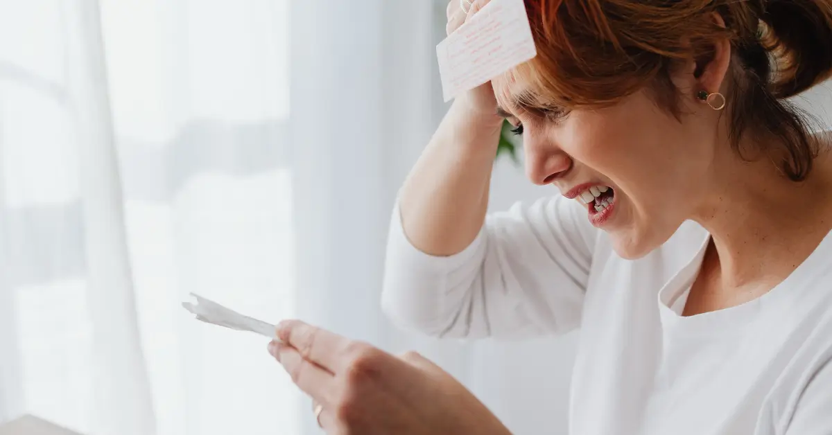 A frustrated woman holds a bill while clutching her head, expressing stress over high water costs A frustrated woman holds a bill while clutching her head, expressing stress over high water costs