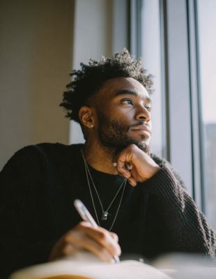 Thoughtful man journaling by a window, reflecting on stress and life balance — illustrating how counselling in Gauteng provides tools to manage anxiety, burnout, and daily overwhelm