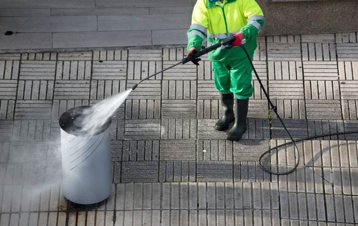 a person powerwashing a garbage can 