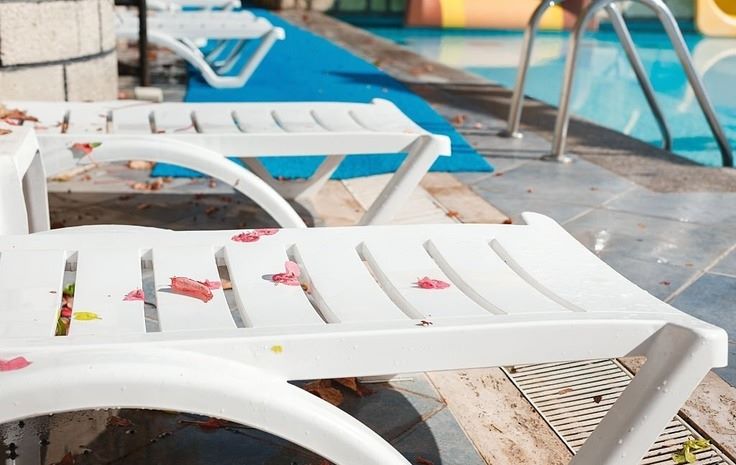 white lounge chairs next to a pool