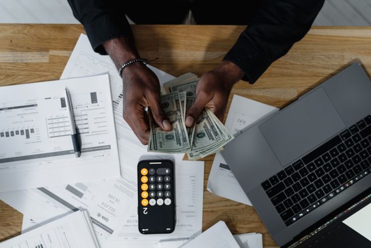a person holding money and calculator
