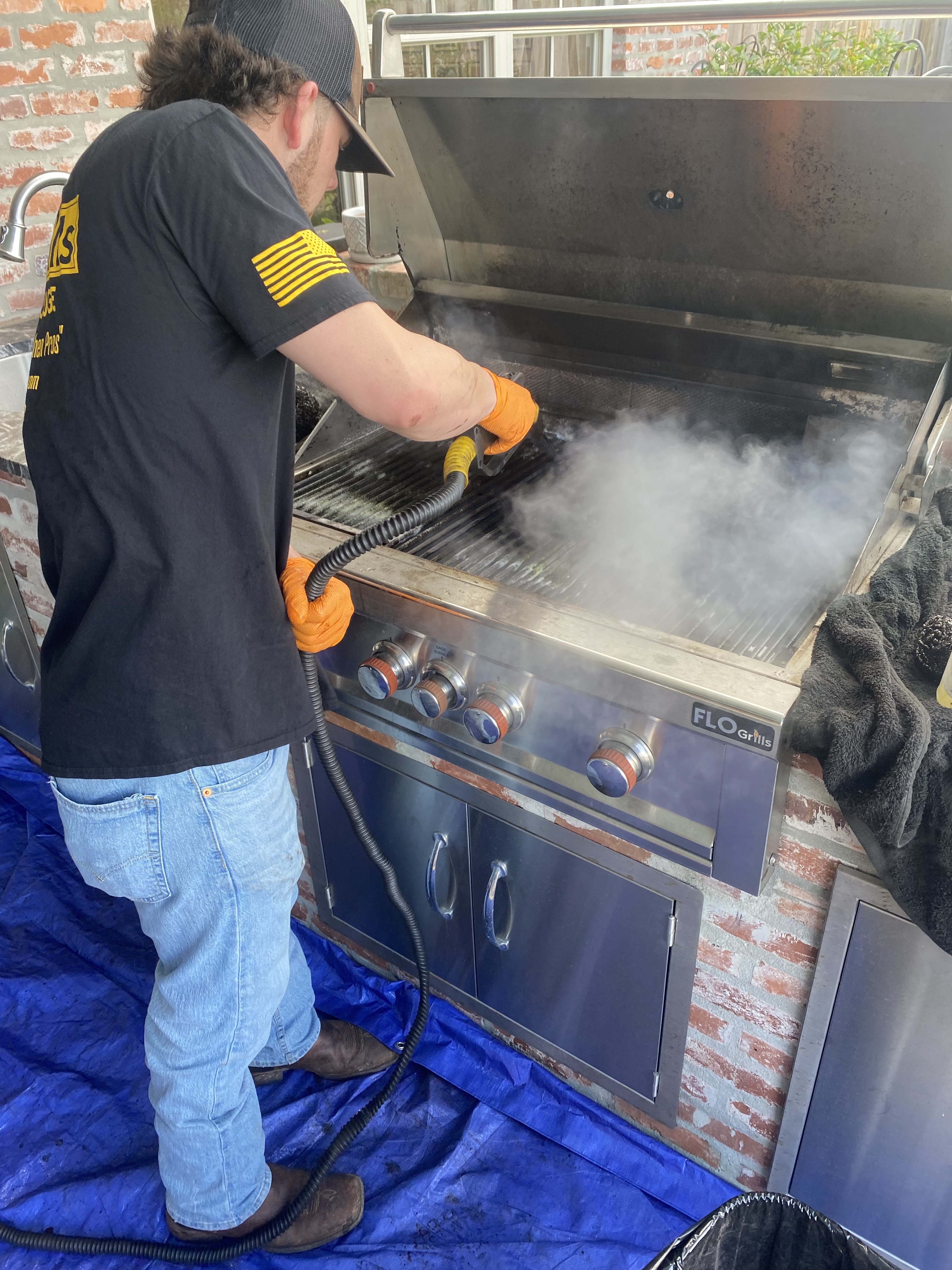 Tech steaming a grill during a deep clean
