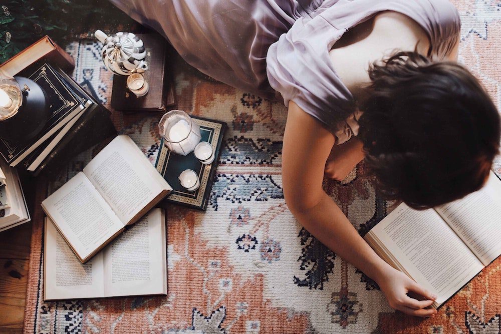 Woman laying on the floor reading books