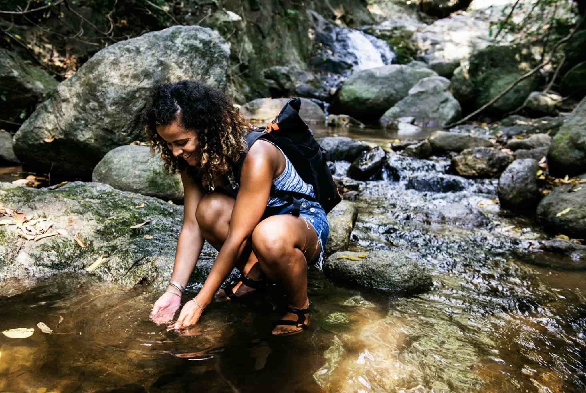 woman drinks water from river