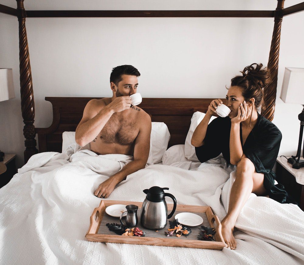 Couple in bed drinking coffee after trying to optimize sleep