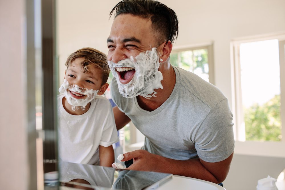 Father and son looking into the mirror laughing