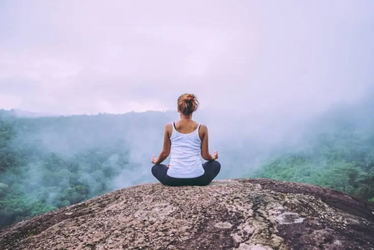 Woman meditating at the top of a hill defining subconscious