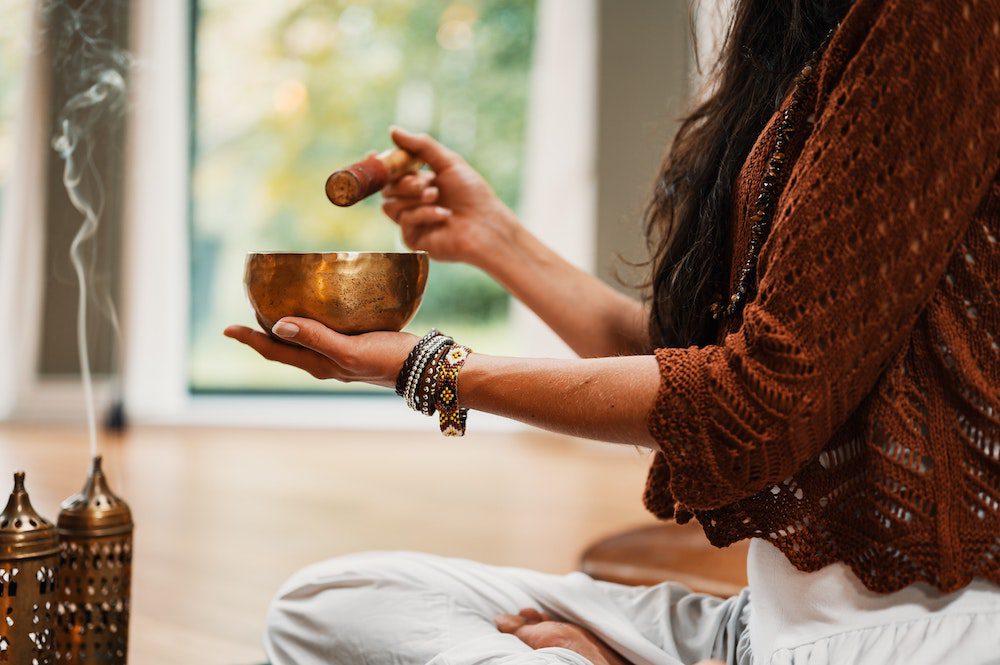 Woman using singing bowl for sound healing