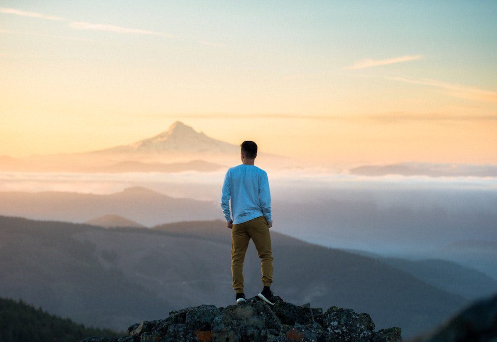 Man standing on a mountain practicing his subconscious power