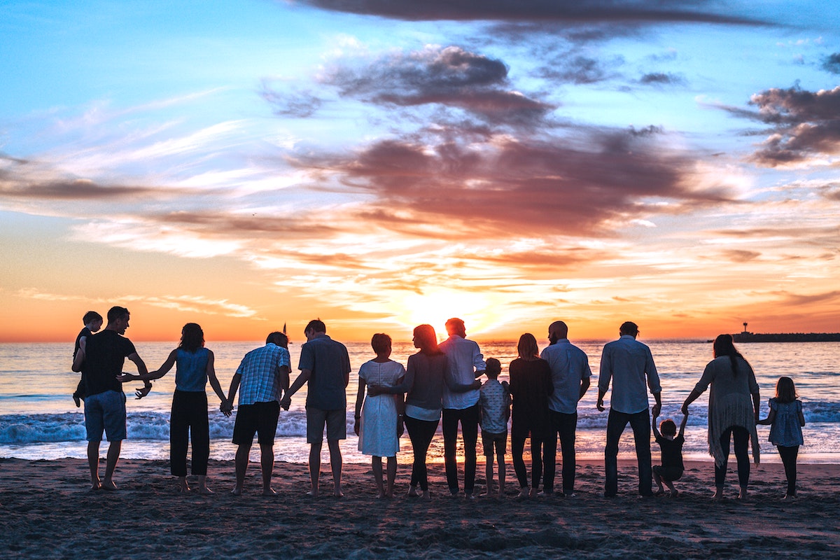 a group of families with kids holding hands on the beach