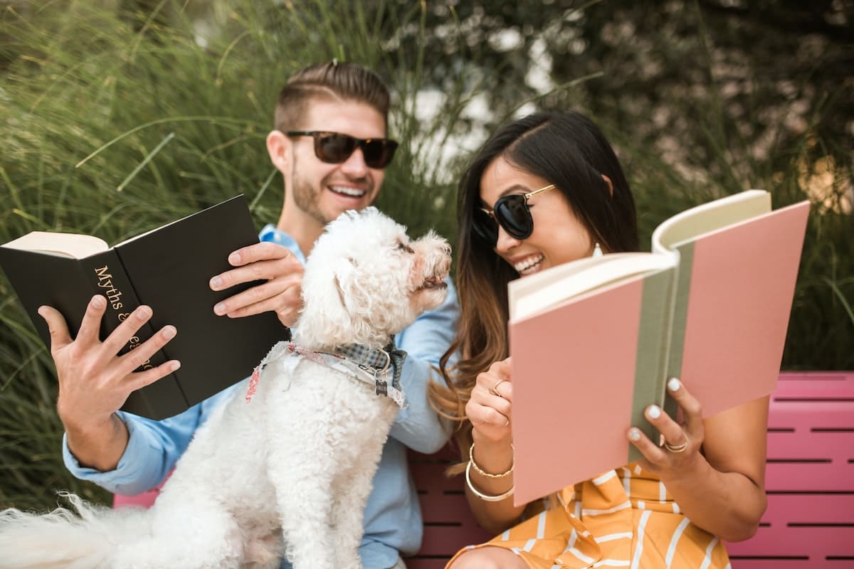 a couple showing pictures in the album to a dog 