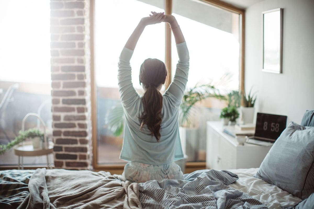 Woman stretching in the morning after learning how to fix sleep schedule.