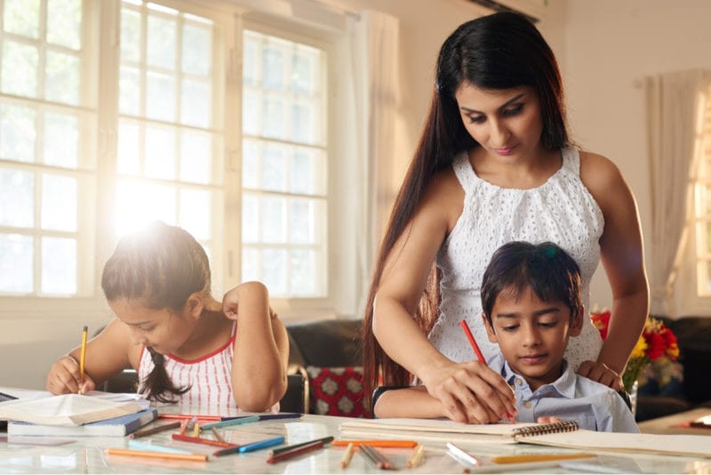 Mother helping her children write