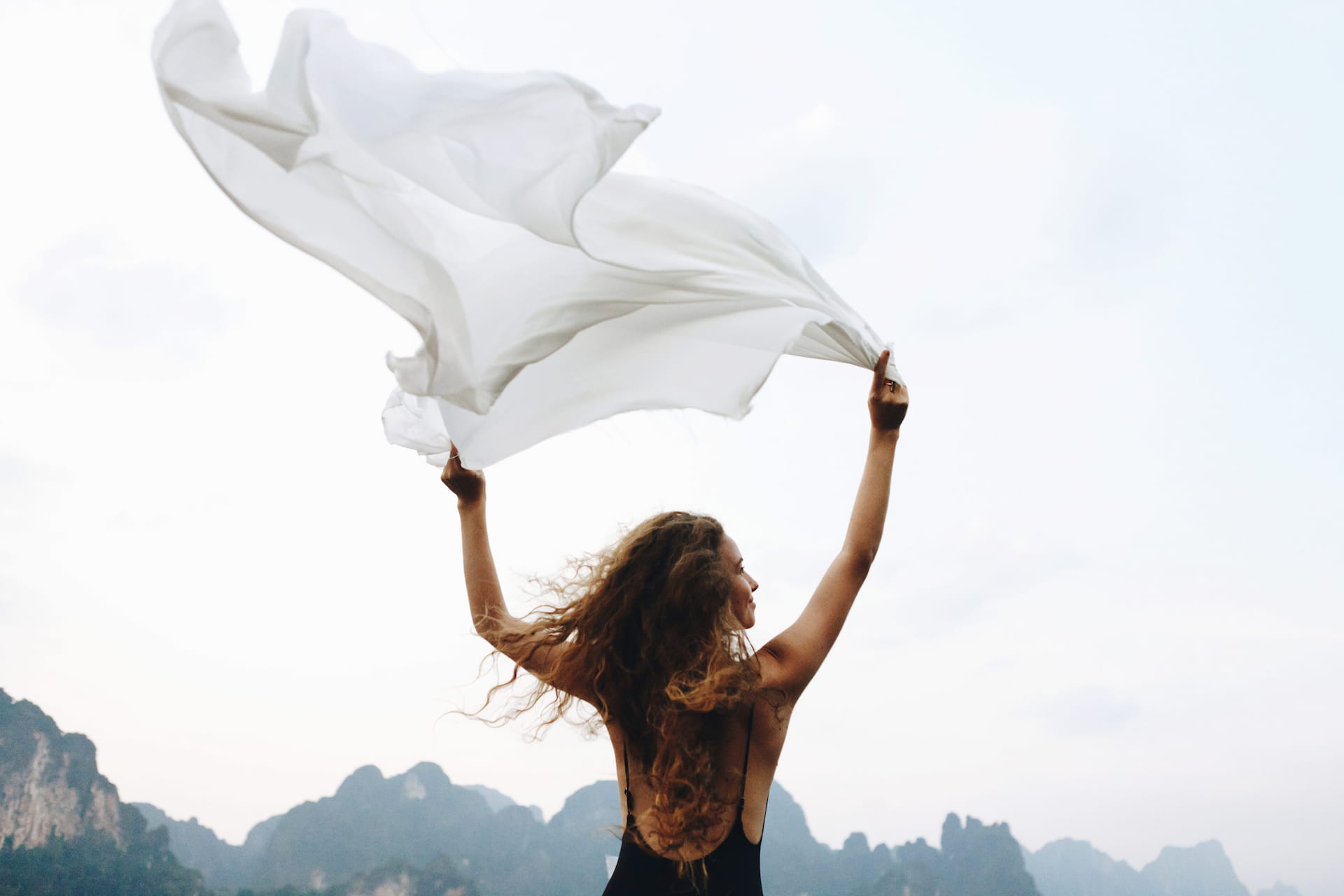 a woman holding a white sheet and waving in the wind