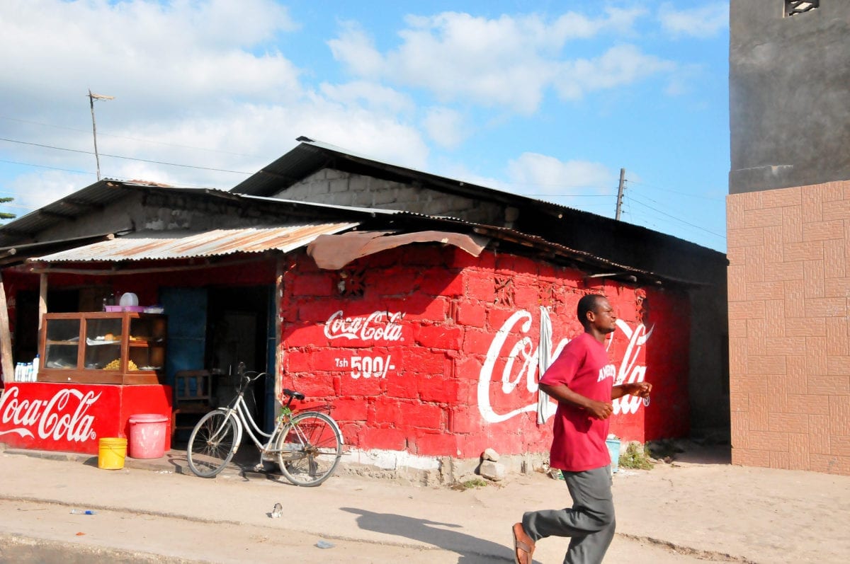 A man running past a coca-cola wall