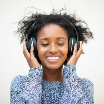 Close up front portrait young african american woman listening to music with headphones and eyes closed