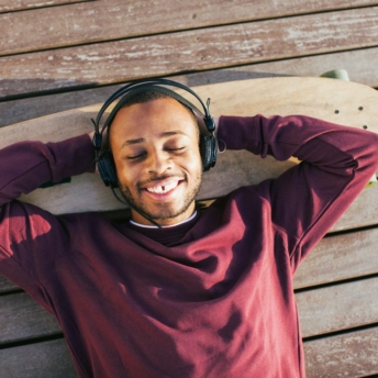Young man listening podcasts with headphone outside.