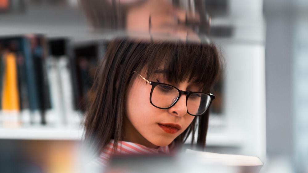 Woman in library looking at a book to read