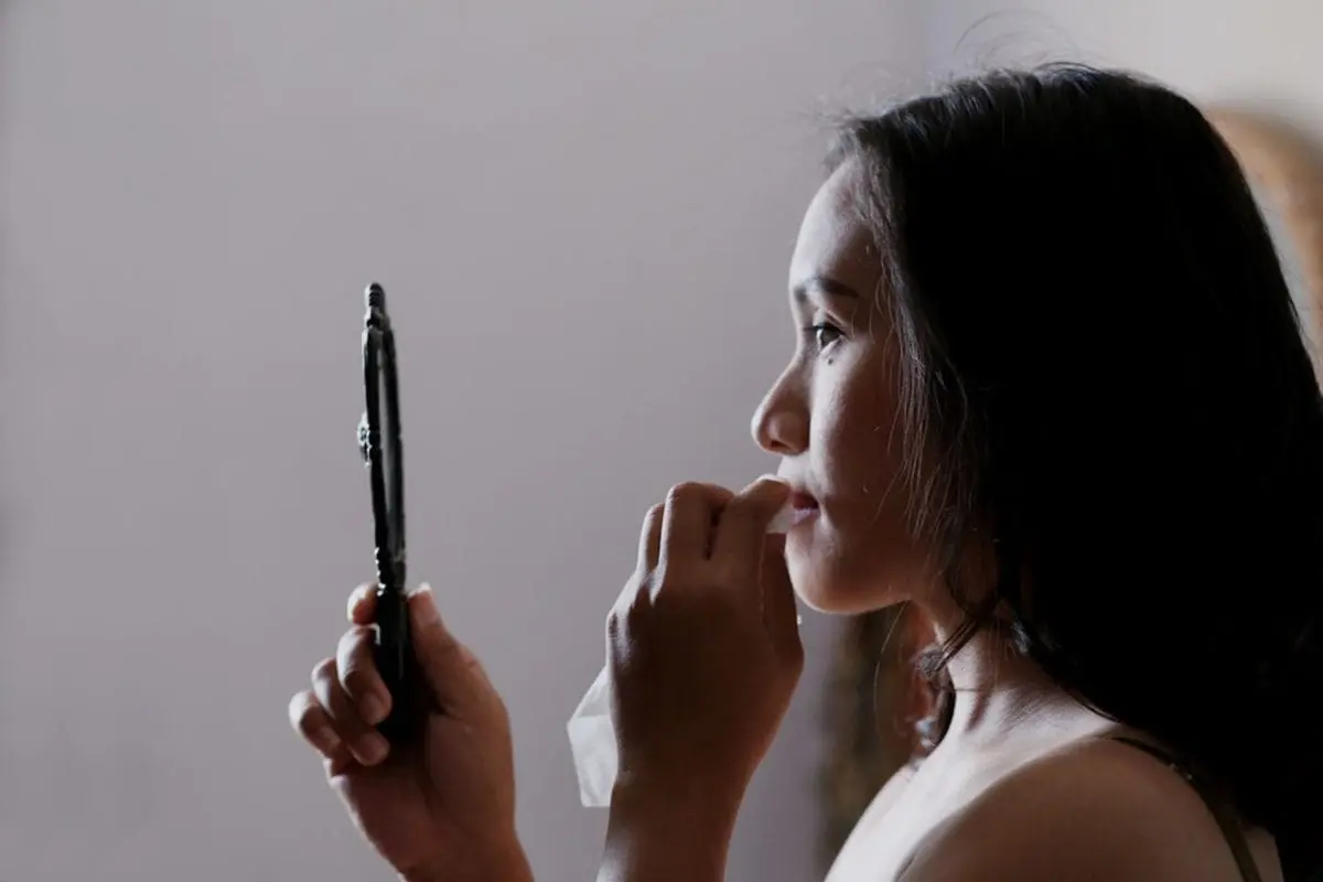 Woman looking into a handheld mirror