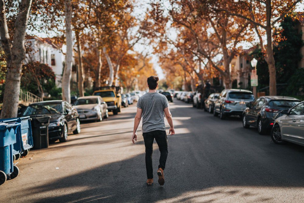 Man walking down the middle of a city street finding it hard to forgive himself