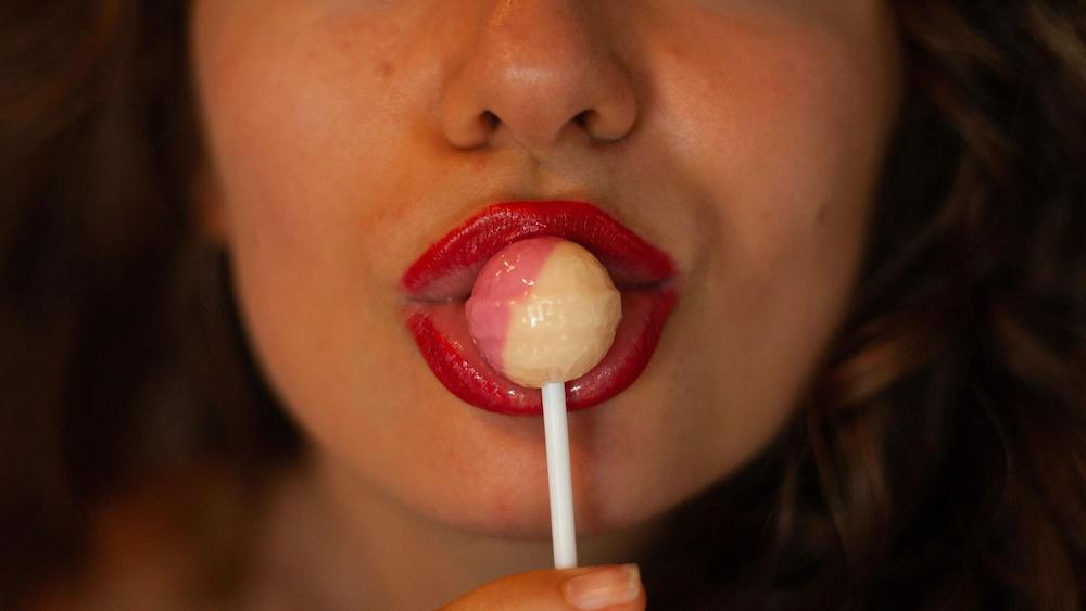 Woman foreplaying by sucking on a lollipop