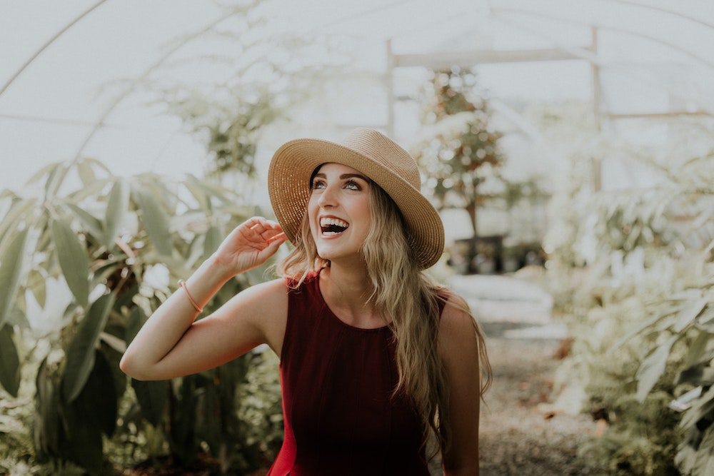 Woman in red dress and sun hat in a greenhouse