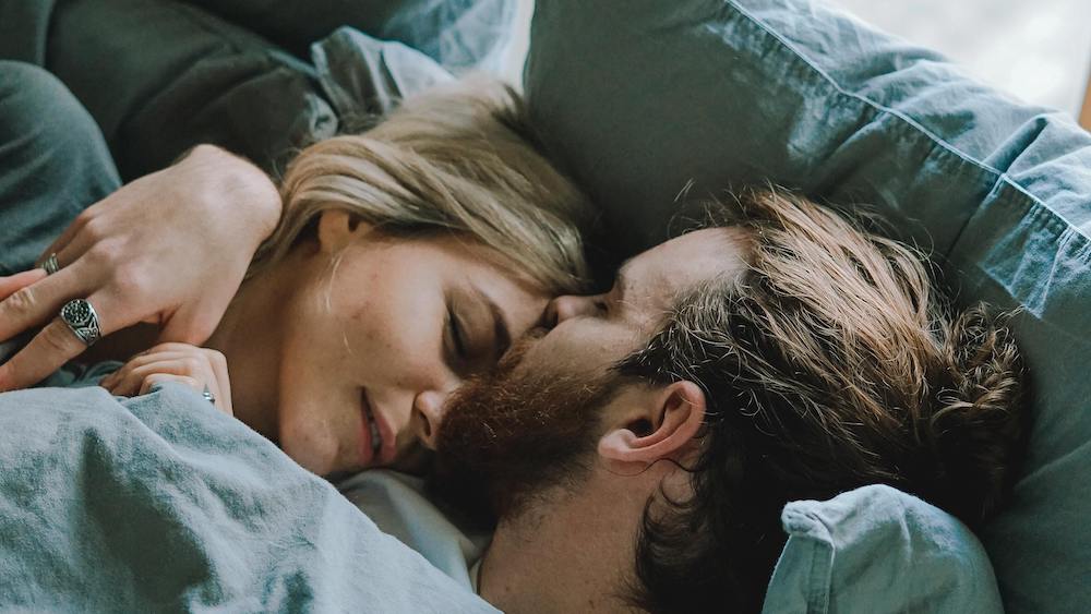 Man kissing woman on forehead in bed