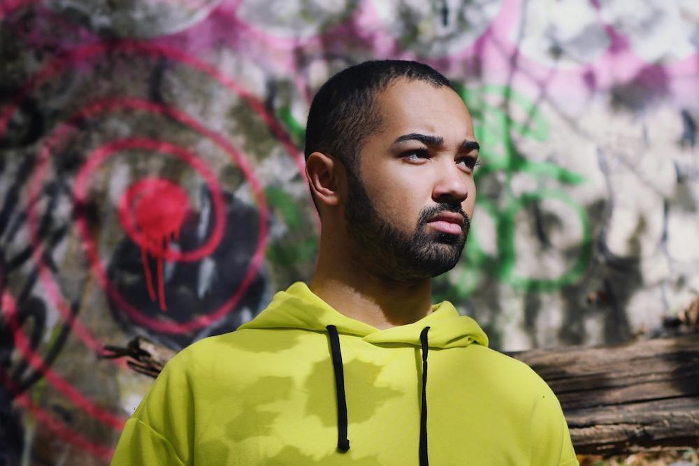 Man wearing a yellow hoodie in front of a colorful wall feeling discomfort