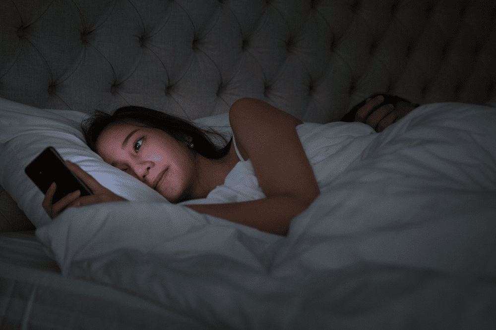 Woman on her phone at night doing revenge bedtime procrastination